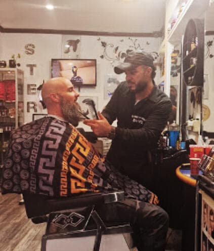 De eigenaar en enige kapper van Kapsalon Basel achter de stoel in zijn zaak